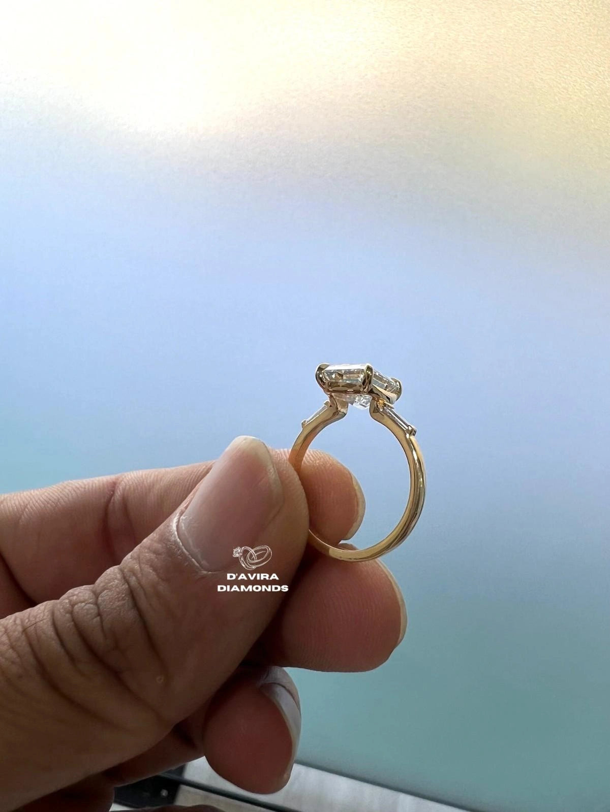 A gold ring with a lab diamond held between fingers