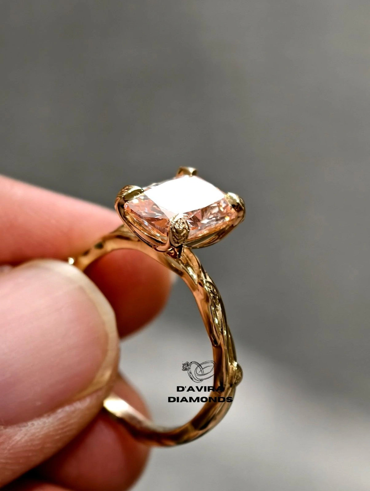 hand holding a yellow gold with a cushion-cut lab diamond ring