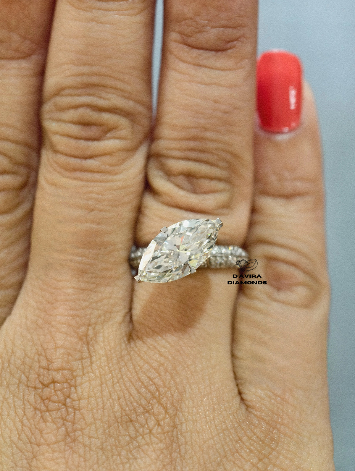 Marquise cut diamond engagement ring with a pave diamond band on a finger