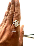 A close-up of a hand wearing a gold ring with oval center stone and smaller side stones
