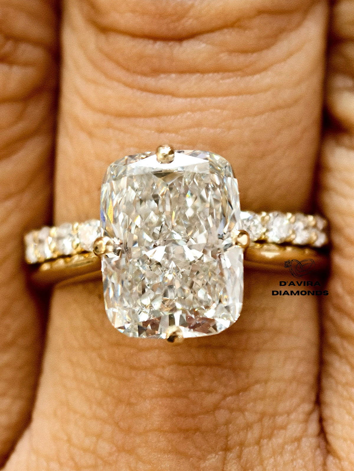 Elongated cushion cut diamond engagement ring with a pave diamond band on a finger