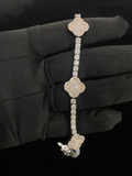 A three-piece diamond bracelet with clover-shaped motifs and a pave band, held by a hand wearing a black glove
