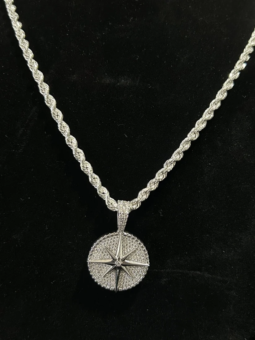 Close-up of a silver diamond-encrusted compass pendant necklace