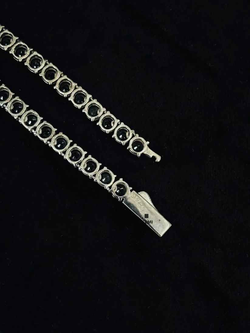 Close-up of a sterling silver black diamond tennis chain showing the secure clasp and tongue closure.