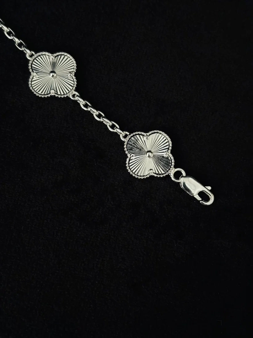 A silver chain bracelet featuring two textured, sunburst-style four-petal flower charms and a lobster clasp