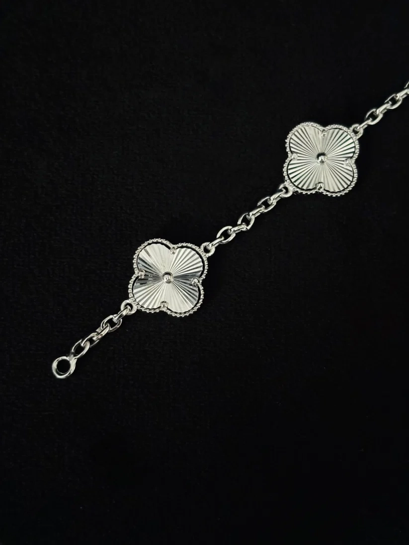 A Close-up view silver bracelet featuring two textured, flower-like clover motifs connected by a delicate chain