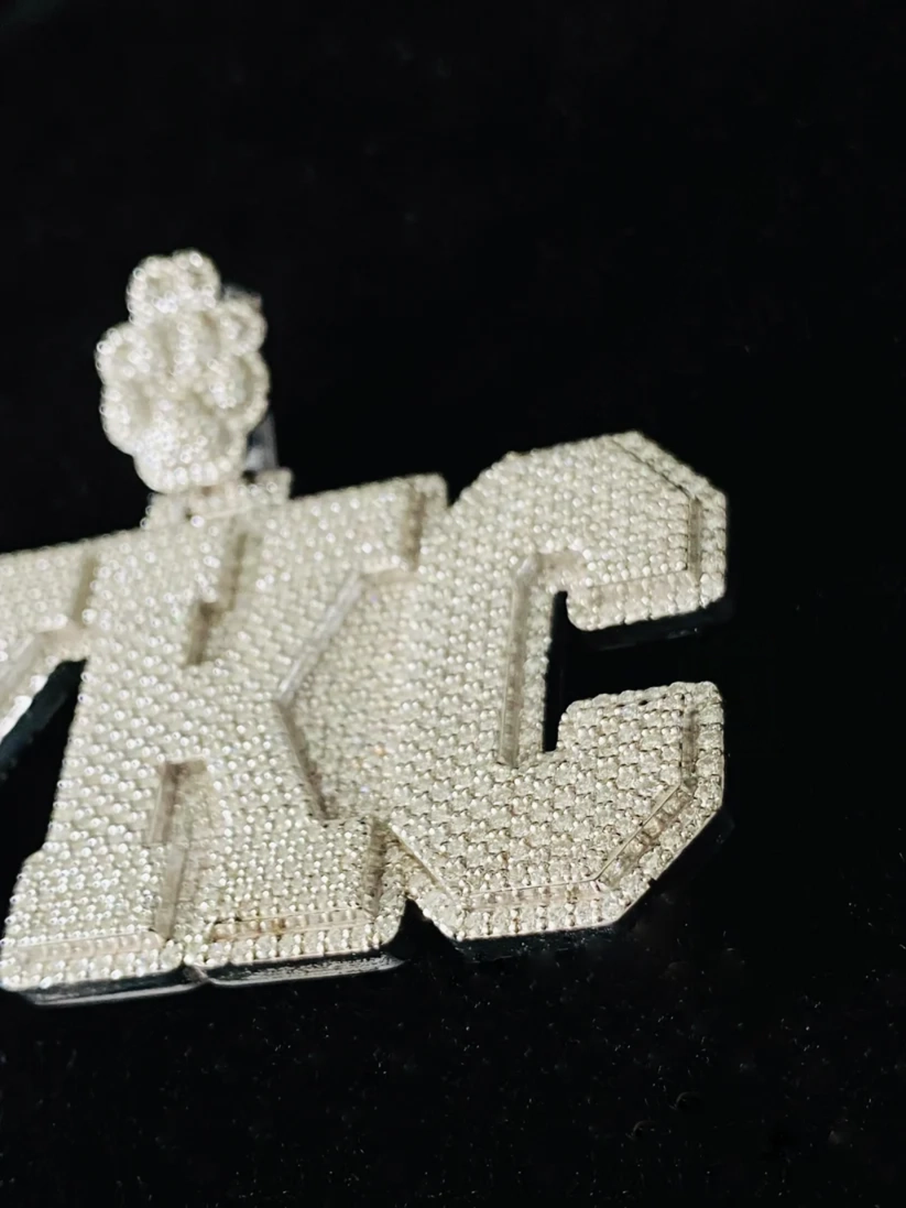 Custom iced out KC letter pendant necklace in sterling silver with pave cubic zirconia stones.
