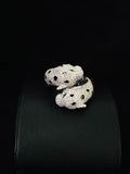 A silver ring designed as a coiled snake, heavily embellished with pave stones and accented with two small green gemstones