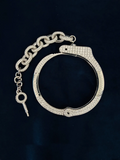 Silver handcuffs encrusted with diamond, chain link extension and key, displayed on a dark navy background