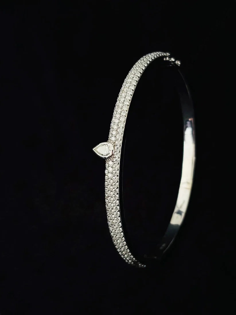pave diamond bangle bracelet featuring a central bezel-set pear-shaped diamond charm