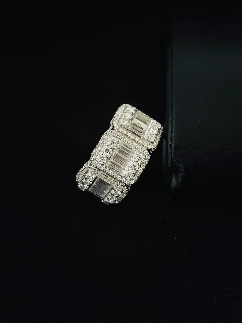 Close-up of a chunky silver iced-out statement ring against a black background