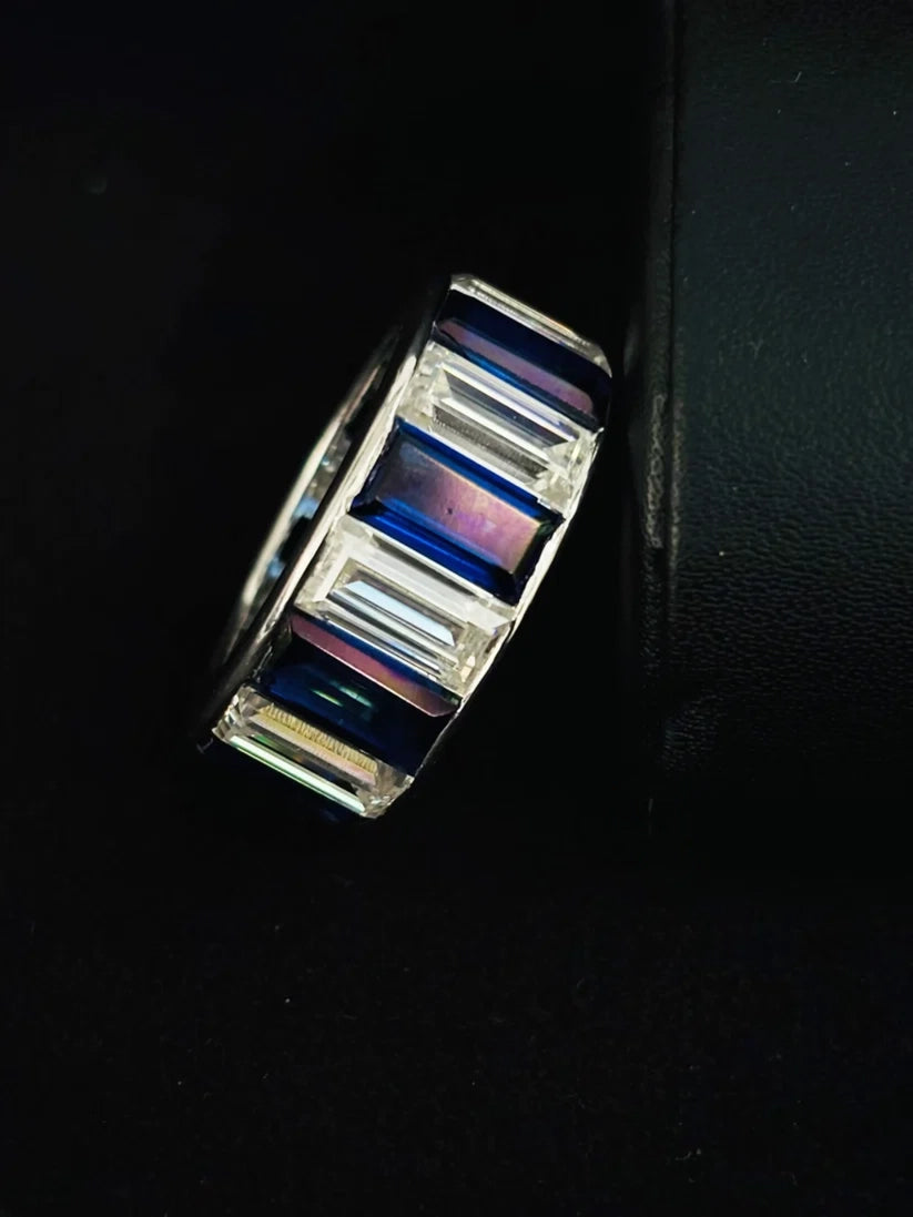 A Close silver band ring featuring baguette-cut iridescent that shift between blue, white diamond