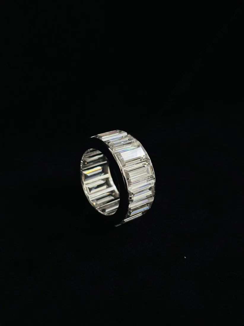 baguette cut moissanite eternity ring in a silver channel setting on a black background