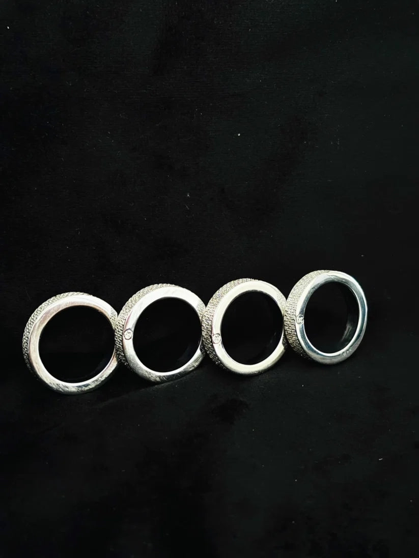 side view Four silver pave diamond wedding band rings on black backdrop.