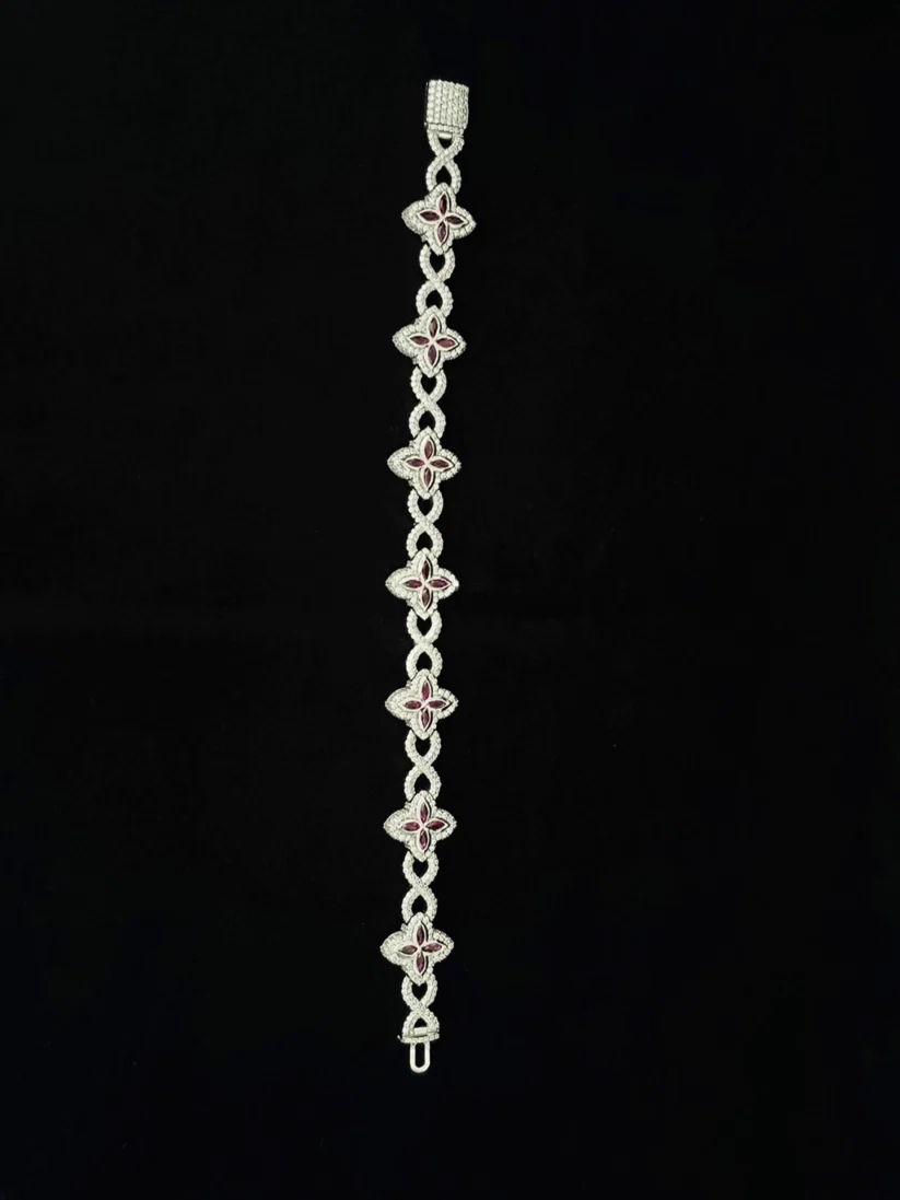 A full showing Silver infinity link bracelet featuring pave diamond settings and pink gemstone flower charms