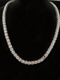 A silver tennis necklace with diamond, displayed on a black velvet mannequin bust