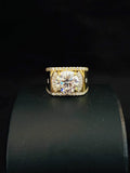 A yellow plated ring with a round-cut clear center stone and smaller accent stones along the band