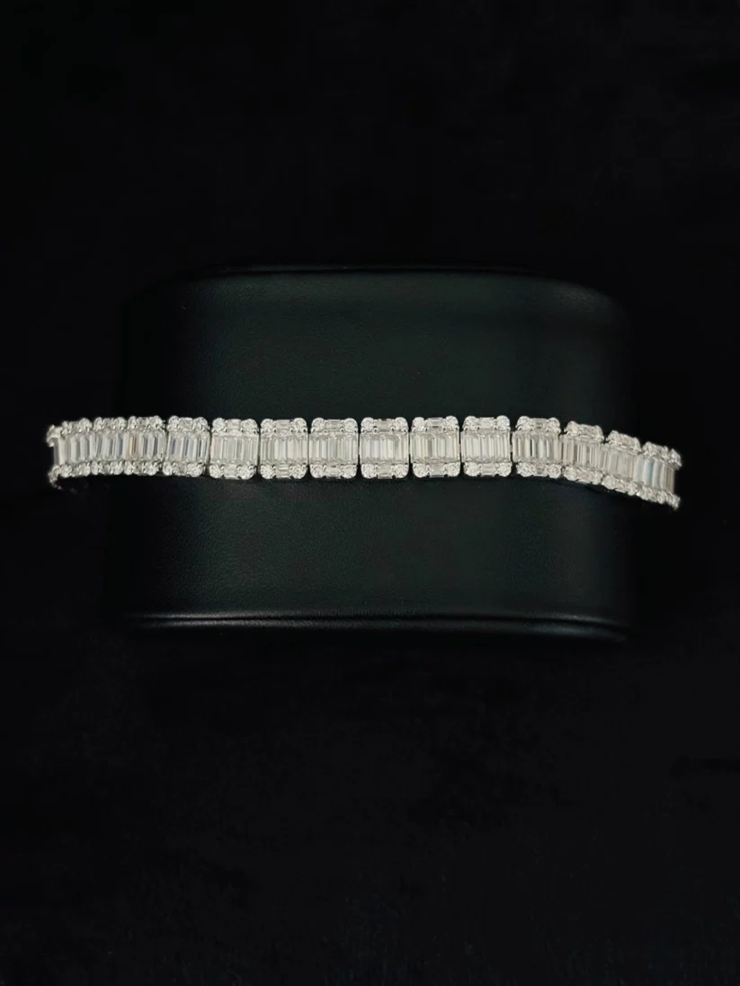 A close-up view Silver diamond baguette tennis bracelet with channel-set rectangular link layout on a black background