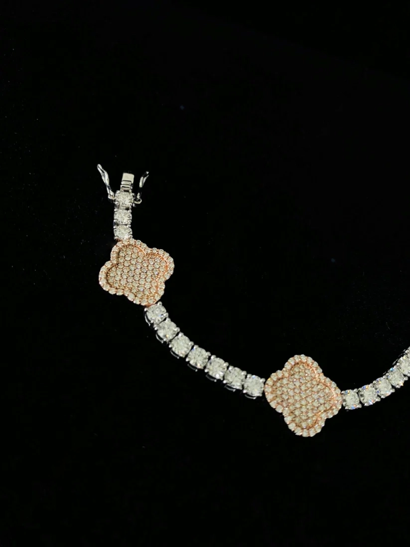 A silver bracelet featuring two pave-set peach-beige flower motifs connected by a row of diamond