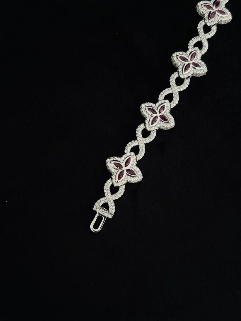 A silver chain bracelet featuring four-link floral motifs with deep red inlay, set 