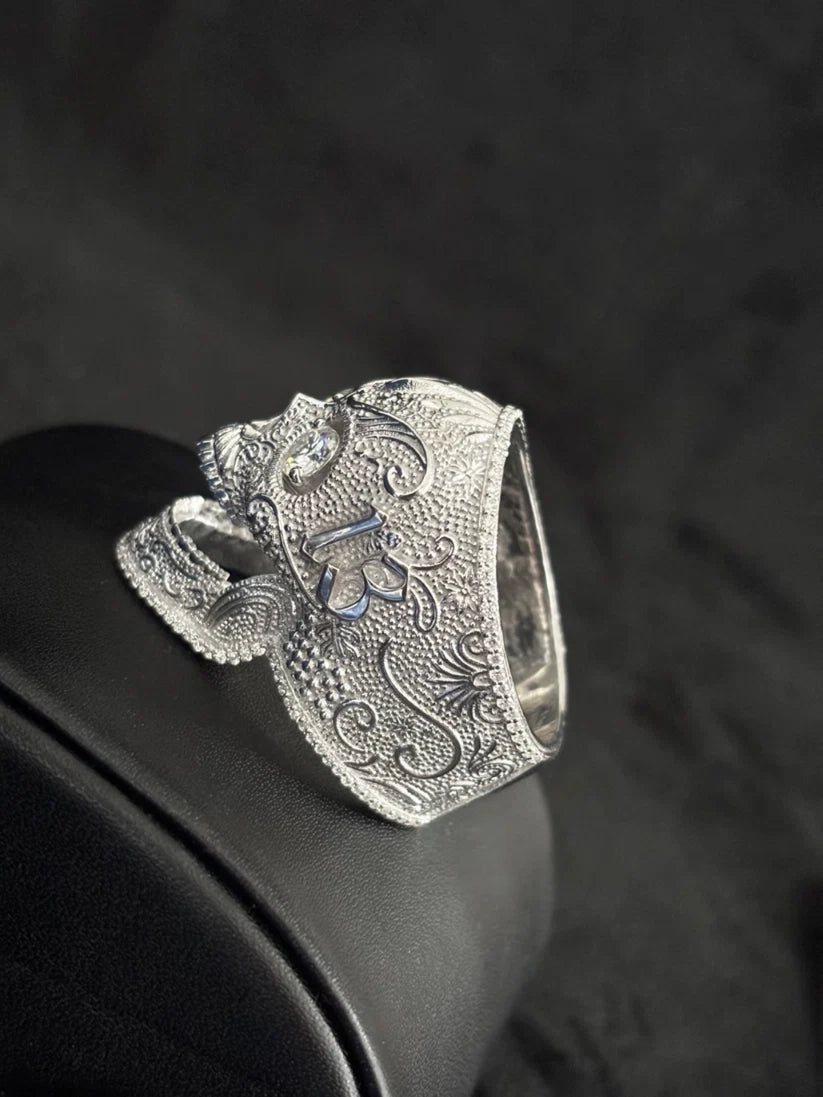 A side view Gothic men's silver skull ring with detailed scrollwork engraving