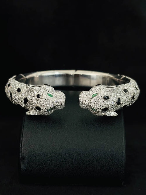 Front view of the Double head panther cuff bracelet in silver with pave diamonds onyx spots and emerald eyes