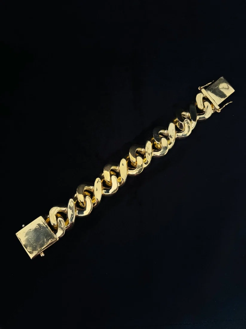 Close-up of a thick statement gold plated link bracelet against a black background