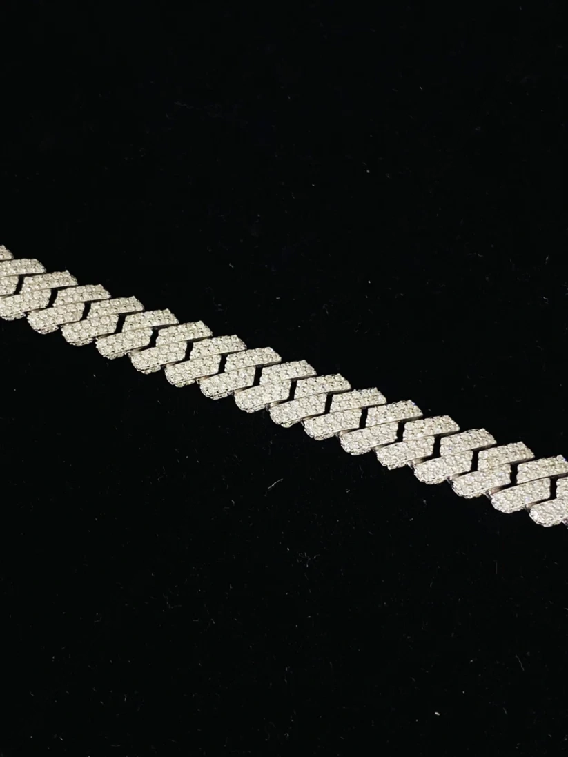 A close-up of a silver chain link bracelet or necklace laid diagonally on a black background