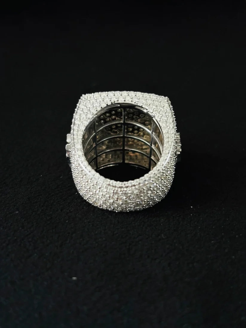 A heavy-duty silver ring heavily with pave stones, photographed from above on a black textured background