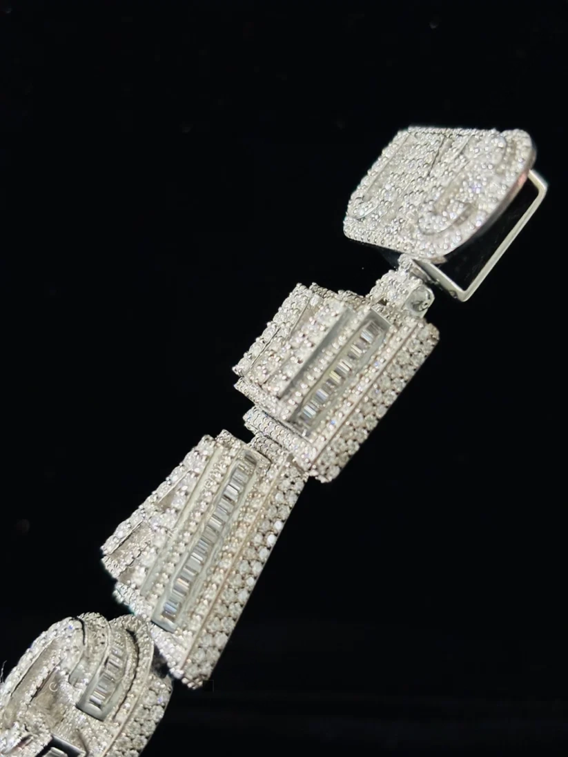 Iced-out silver baguette diamond link pendan on a black background.