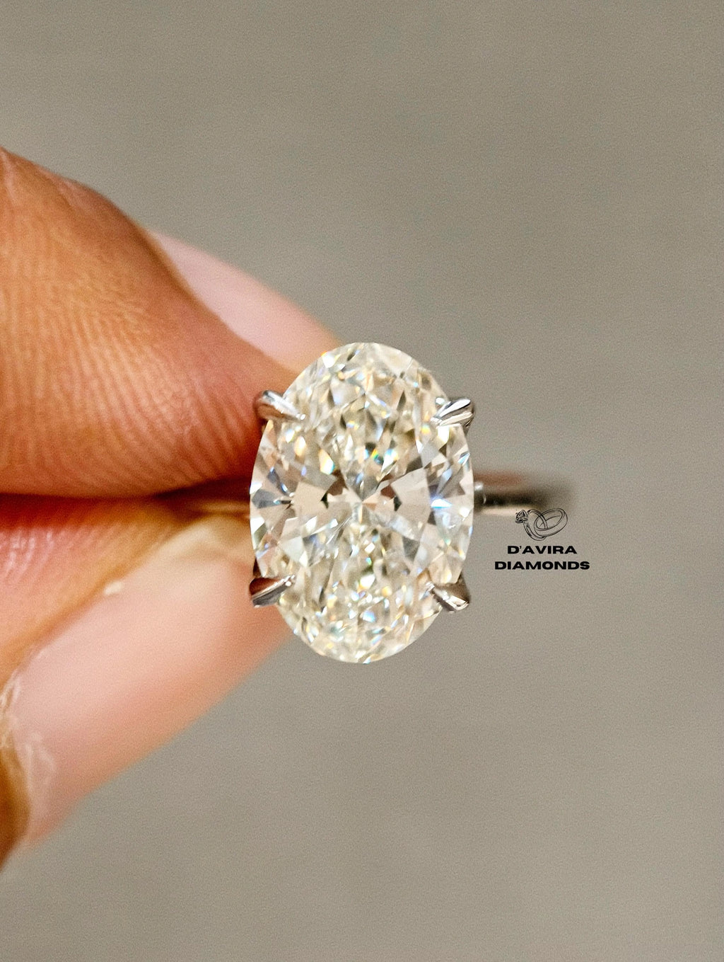 A close-up of a hand holding a brilliant oval-cut diamond ring 