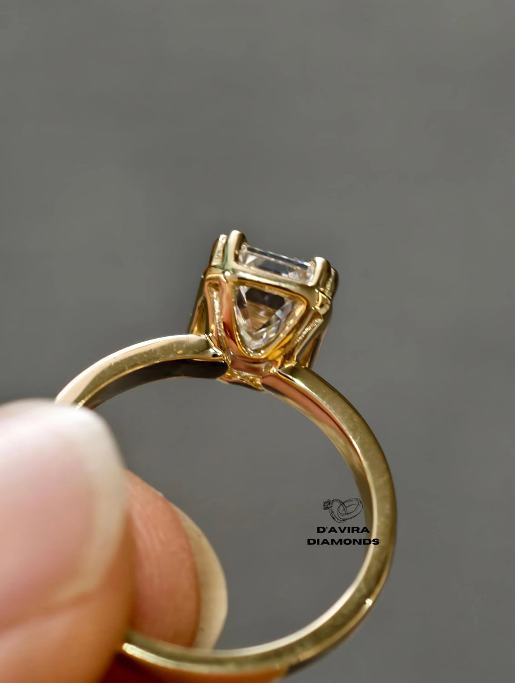 Side profile view of a ring with a emerald cut diamond in a classic basket prong setting