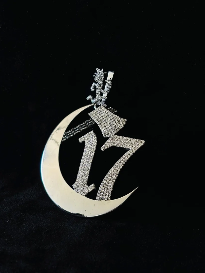 Iced-out sterling silver hip hop pendant with a crescent moon, hatchetman character, and number 17.
