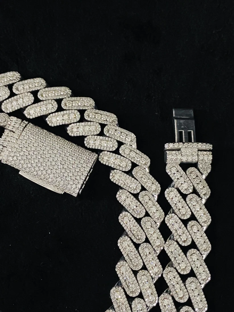 A luxury white gold Cuban link chain heavily set with pave diamonds featuring a detailed view of the diamond lock clasp
