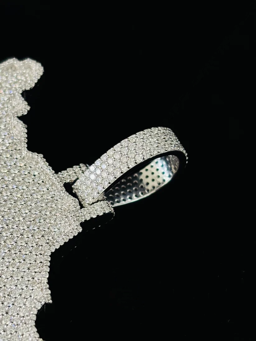 Close-up profile view of a custom iced-out diamond pendant with a micro-pavé iced bail on a black background.
