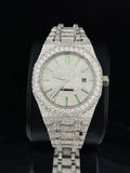 Silver-toned luxury watch covered in pave diamonds with glowing green stick indices and automatic movement dial