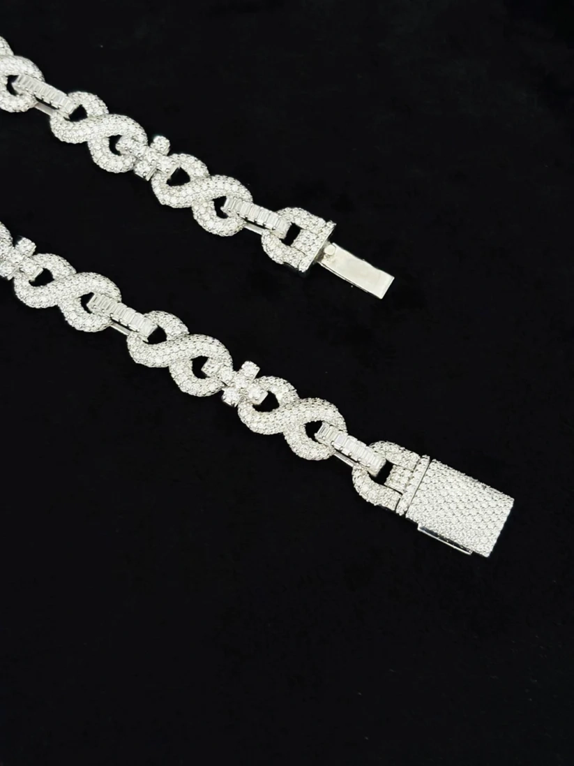 Men's solid silver infinity loop statement chain necklace coiled on a black background