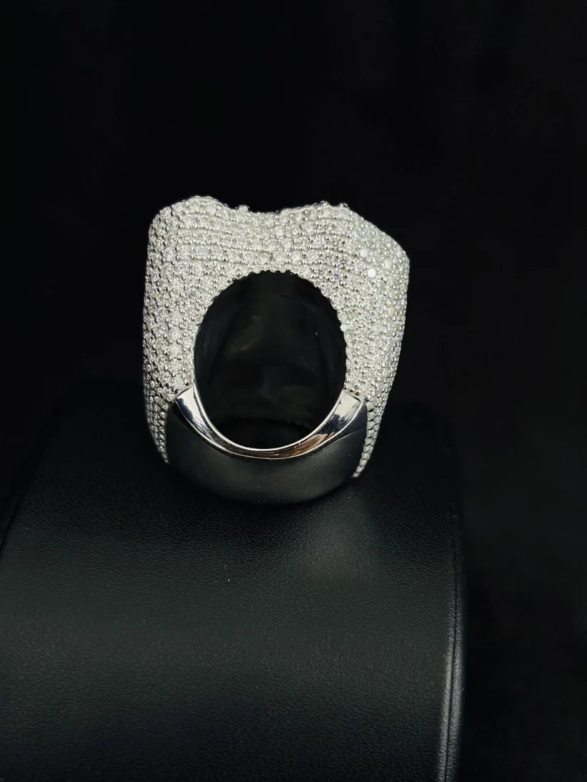 Luxury diamond-encrusted cocktail ring in white gold sitting on a black display stand.
