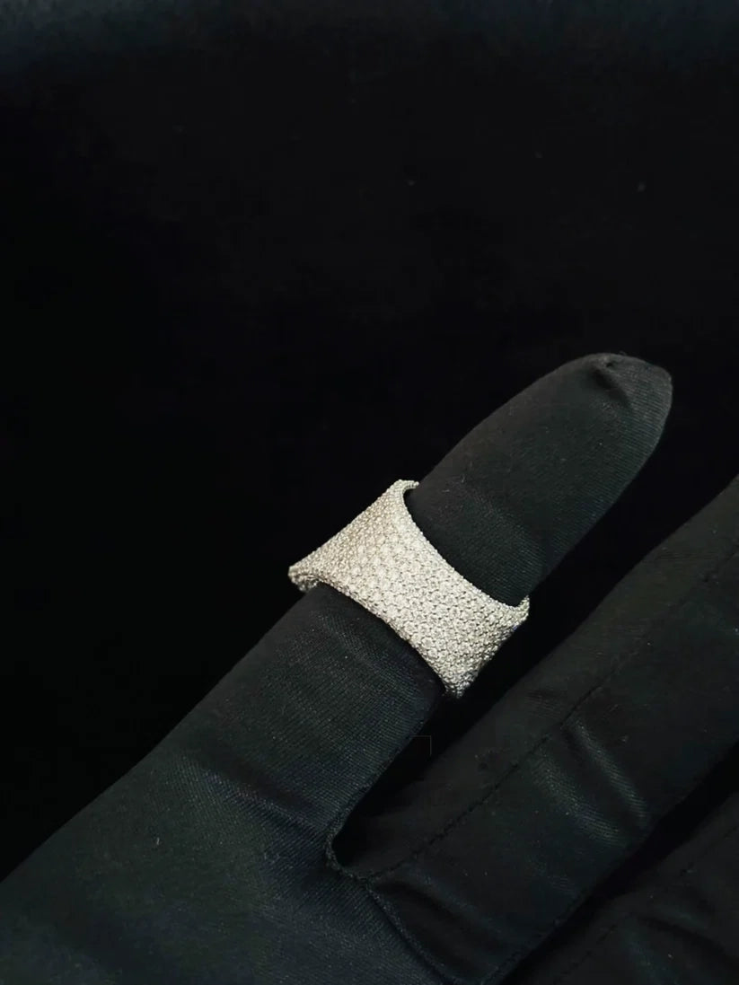 A silver ring with a textured, pave-like surface, shown on a black finger form or gloved hand