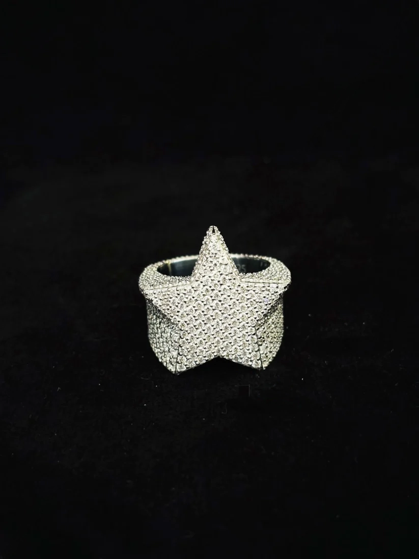 A silver ring shaped like a five-pointed star, heavily embellished with diamond