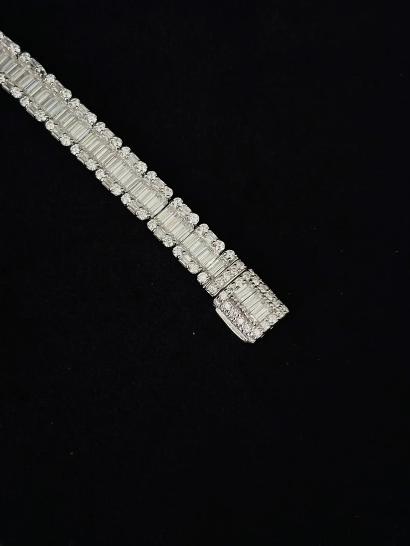 Silver baguette diamond tennis bracelet with round borders on a black background