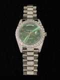 Silver luxury watch featuring a green Roman numeral dial oversized diamond bezel and diamond-pave band