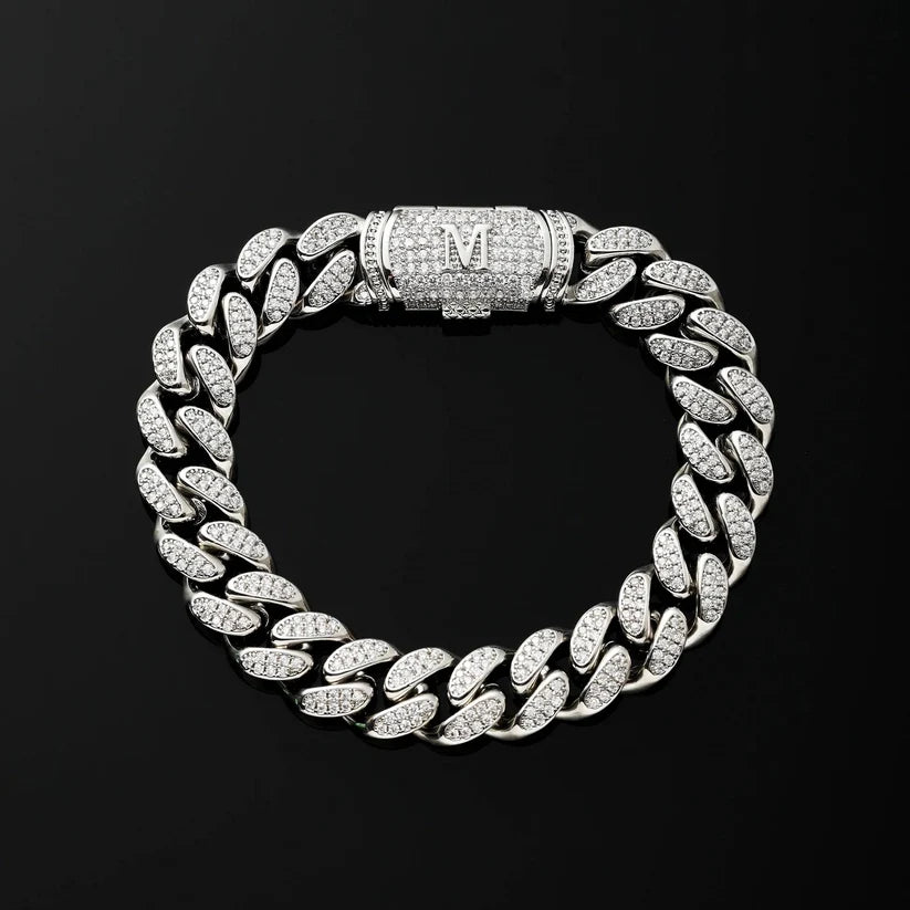 A silver Cuban link chain bracelet paved, featuring a central clasp engraved with the letter 'M'