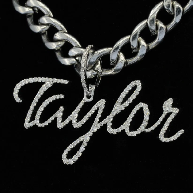 A silver-toned chain necklace with a cursive script pendant spelling 'Taylor', set against a solid black background.