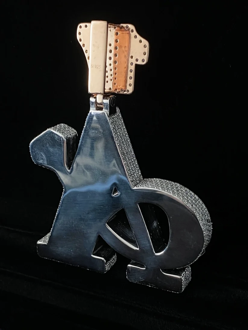 Custom iced out 3D letter pendant with pave diamonds on a black background