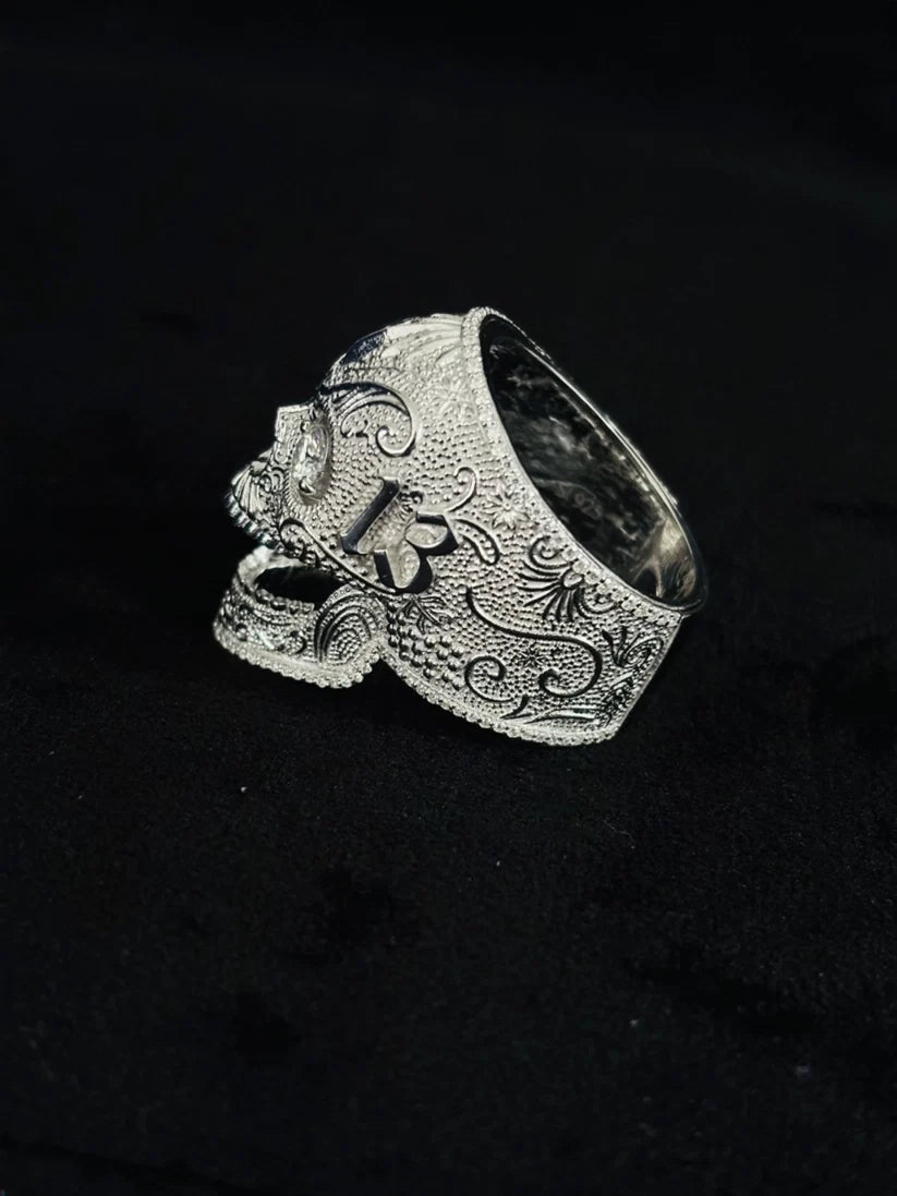 A side view Gothic men's silver skull ring with detailed scrollwork engraving
