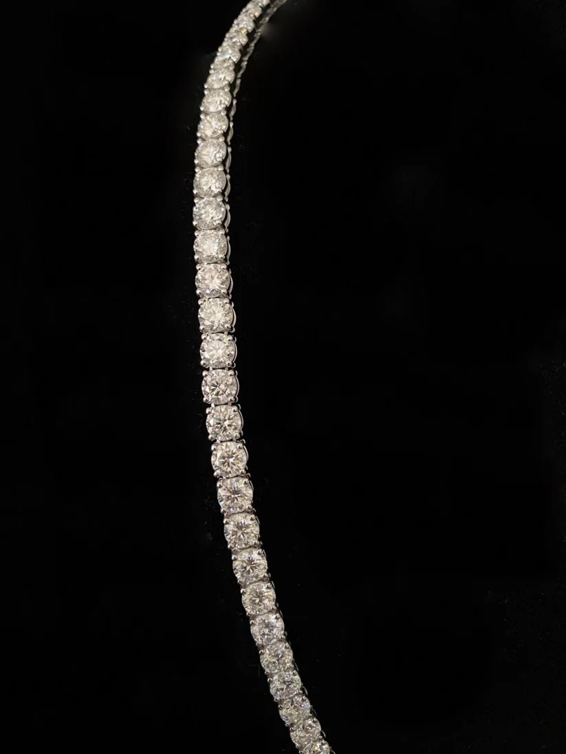 A close-up of a tennis chain featuring round-cut clear stones set in a silver metal