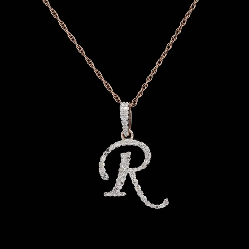Cursive script letter R initial pendant necklace in rose gold with pavé diamond on a thin rope chain.