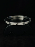 A front view silver bangle bracelet with pave-set clear diamond and round screw-like center details