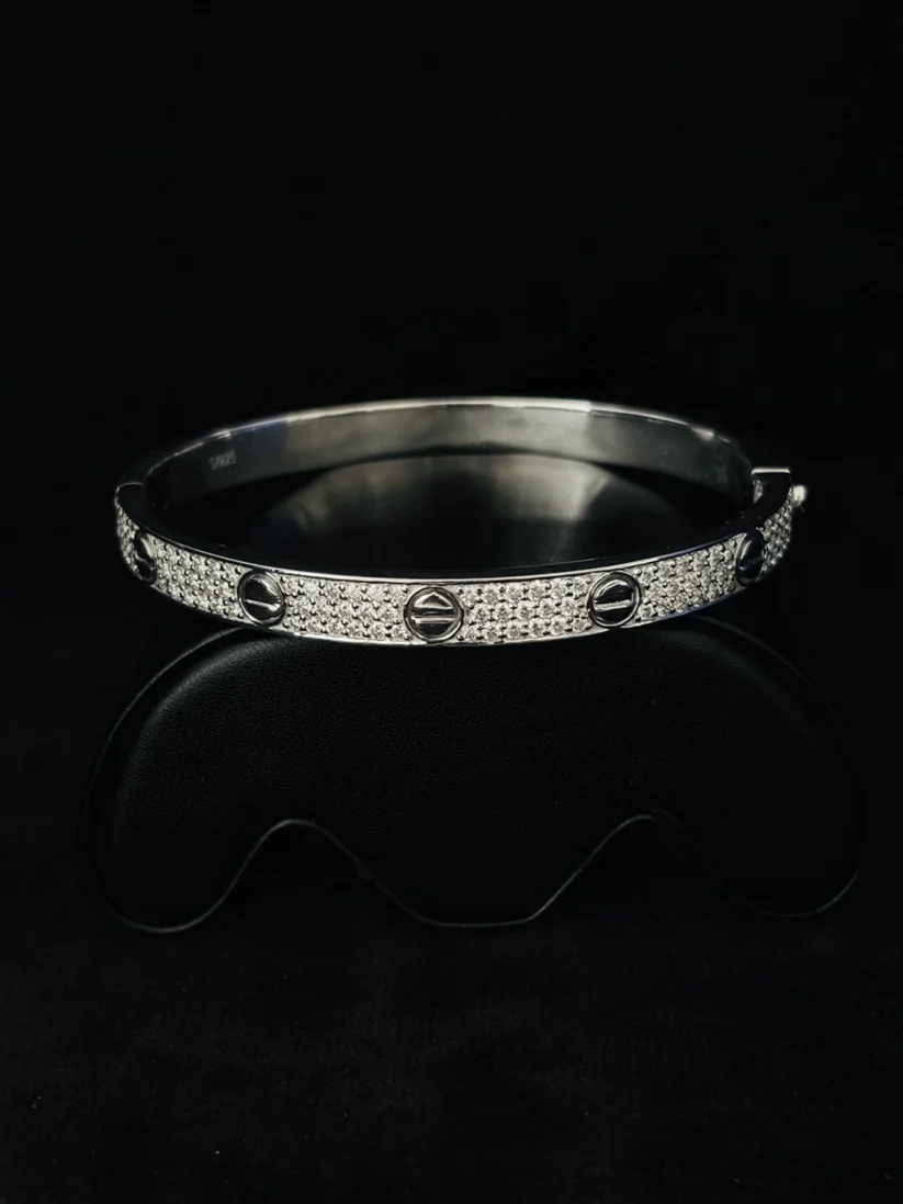 A front view silver bangle bracelet with pave-set clear diamond and round screw-like center details